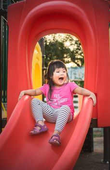 little girl having fun to play slider in the playground in summer time