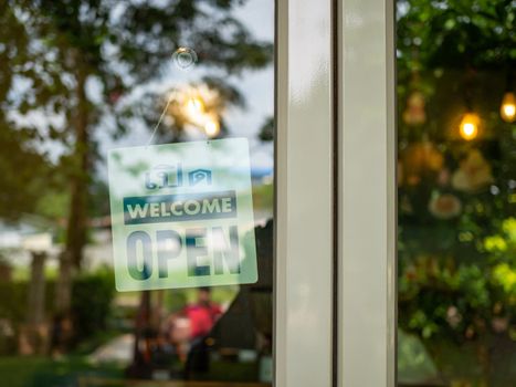 An open sign hangs behind the glass of a shop door. The idea of starting a business. busisness concept.