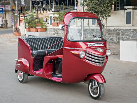 Pune,Maharashtra,India-January 11th,2017: Modified and decorated red colored three wheeler autorikshaw on the street.