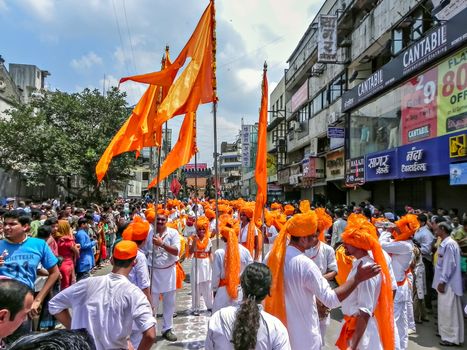 Pune,Maharashtra,India-September 22nd,2010: Group of youths bearing traditional huge orange flags collectively marching during Ganapati procession.