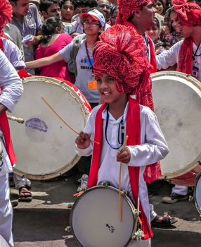 Pune,Maharashtra,India-September 22nd,2010: Little boy with red turban beating traditional tasha during festival procession of ganesh.