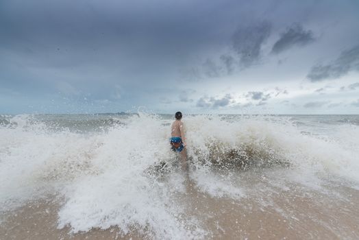 An Asian boy has felt happy and fun on the beach with a cloudy sky.