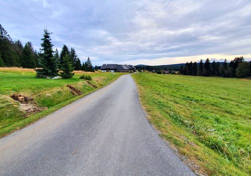 Country road near Kvilda village between meadows in Sumava National Park with beautiful sunset light. 