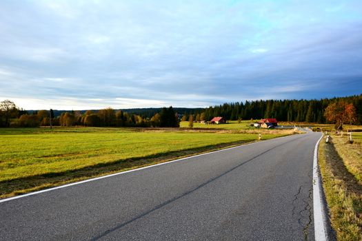 Country road near Kvilda village between meadows in Sumava National Park with beautiful sunset light. 