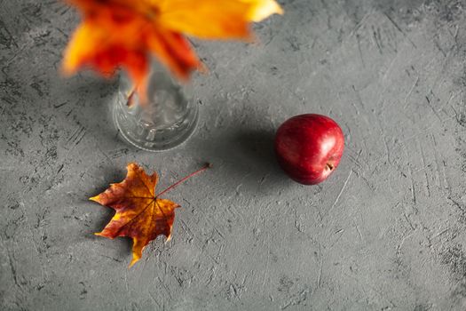 Autumn marple leaves and Ripe garden red apples on gray concrete. Fruits concept of the fall harvest. Space for text.