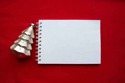 Notebook and silver Christmas tree on a red background. The concept of a New year.