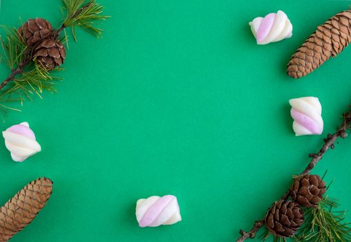 Three pine cones and green fir branches lie on a green background. The concept of the New year and Christmas.