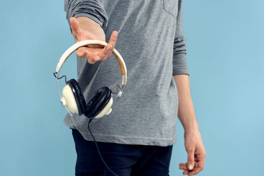 Man holding headphones in his hands music lifestyle technology blue background. High quality photo