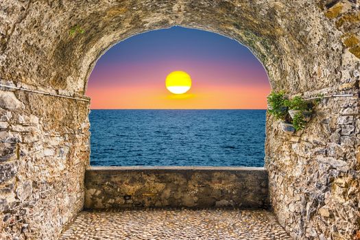 Scenic rock arch balcony overlooking a scenic sunset by the mediterranean sea, Italy