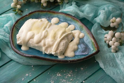 Bowl of organic fresh cottage cheese and sour cream on teal table