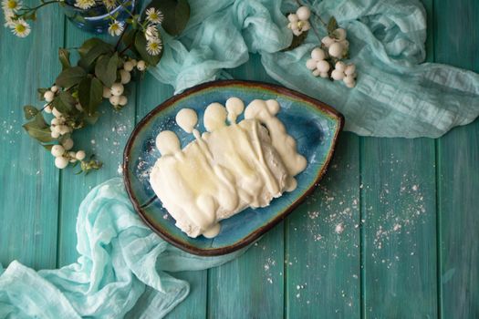 bowl with fresh cottage cheese with sour cream and sugar, in blue oval bowl with grainy cottage cheese on wooden turquoise table, top view