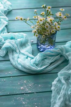 Blooming chamomile flowers on a teal blue wooden background, vertical image