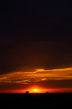 Heavy cloudy sky at sunset. Orange line of light between black clouds. A landscape of beautiful nature.