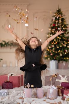 Little girl throws confetti. Christmas magic. Joyful moments of a happy childhood.