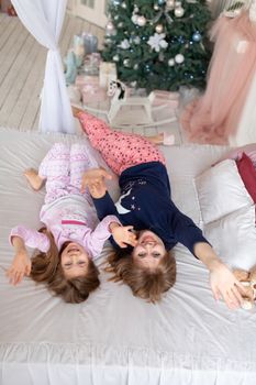 Little girl spends time playing with mom while lying in bed.