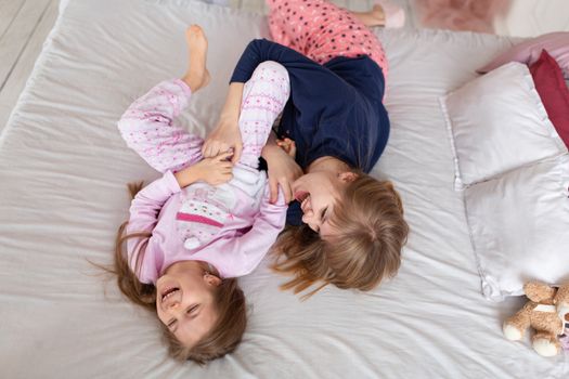 Little girl spends time playing with mom while lying in bed.