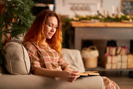 A cute girl is reading a book in a warm and cozy atmosphere. Relaxation and privacy concept.