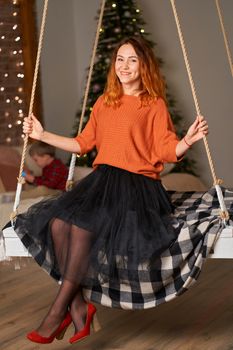 A beautiful redhead girl is swinging in her room on Christmas night.