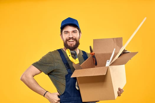 A man in a working form a box with loading tools yellow background. High quality photo