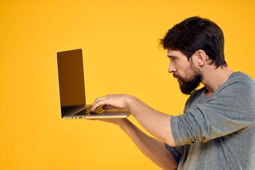 man with laptop wireless technology internet lifestyle work yellow isolated background. High quality photo