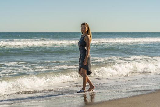 A gorgeous young blonde female enjoys a day at the beach alone