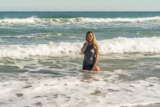 A gorgeous young blonde female enjoys a day at the beach alone