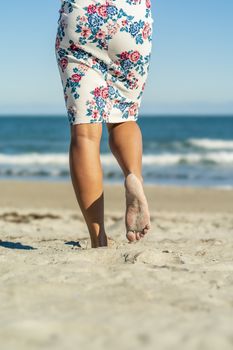 A gorgeous model walks in the sand at the beach on a beautiful day