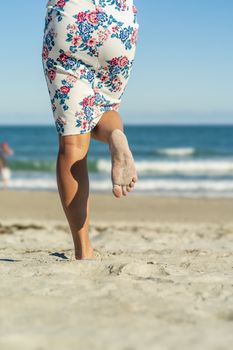 A gorgeous model walks in the sand at the beach on a beautiful day