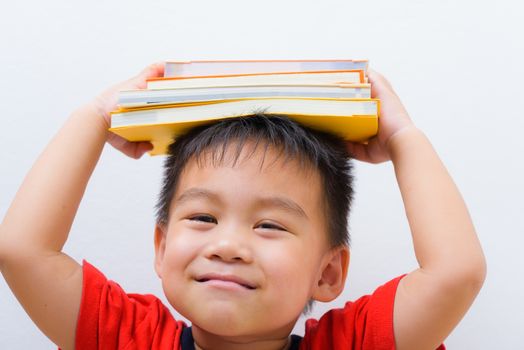 Back to school, Asian student boy kid stack book balanced on head and on white wall background, Education concept