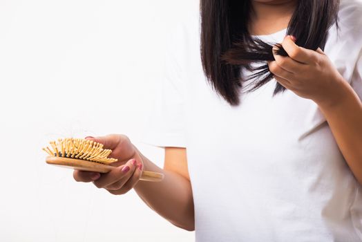 Asian woman unhappy weak hair her hold hairbrush with damaged long loss hair in the comb brush on hand and she looking to hair, studio shot isolated on white background, medicine health care concept