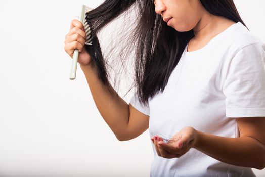 Asian woman weak hair problem her use comb hairbrush brush her hair and showing damaged long loss hair from the brush on hand, studio shot isolated on white background, Medicine health care concept