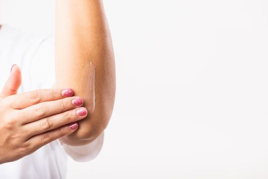 Closeup young Asian woman applies lotion cream on her elbow, studio shot isolated on white background, Healthcare medical and hygiene skin body care concept