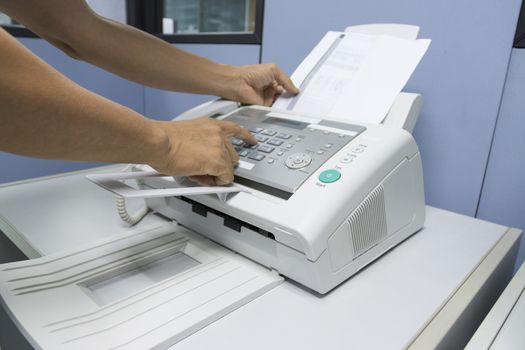 hand man are using a fax machine in the office, equipment for data transmission.