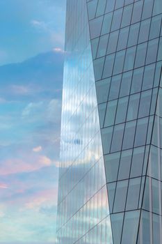 Colorful cloudy sky reflected in the exterior glass facade of a modern corporate building