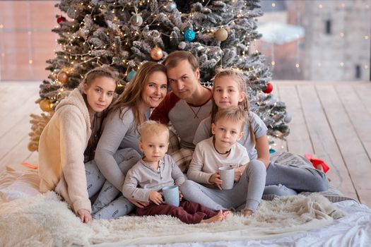 Happy family with kids having fun and opening presents near christmas tree.