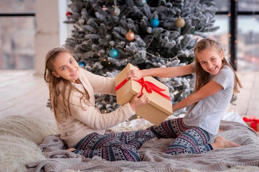 Happy kids having fun and opening presents near christmas tree.