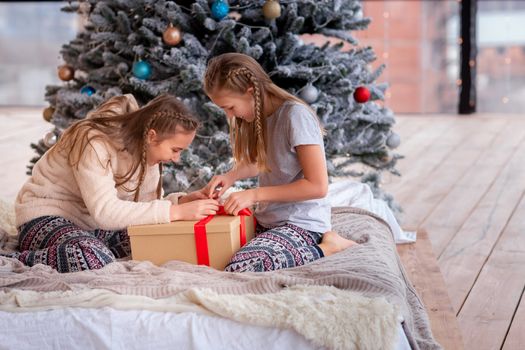 Happy kids having fun and opening presents near christmas tree.