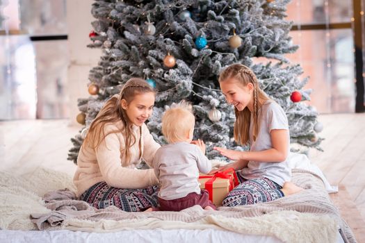 Happy kids having fun and opening presents near christmas tree.