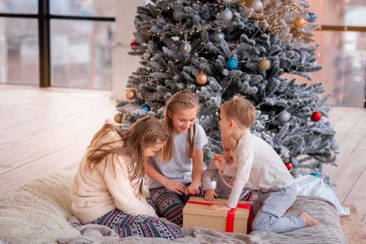 Happy kids having fun and opening presents near christmas tree.