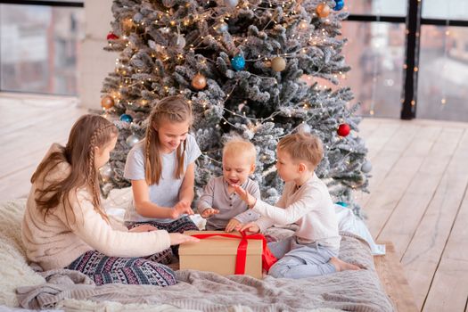 Happy kids having fun and opening presents near christmas tree.