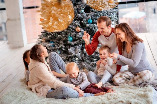 Happy family with kids having fun and opening presents near christmas tree.