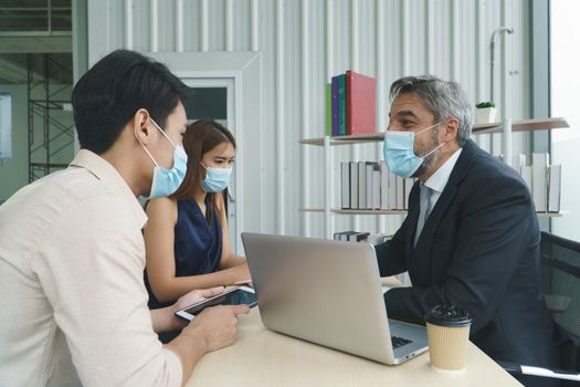 Business people wear a protective mask to work together in the company office. social distancing is the new normal. The concept of preventing the spread of coronavirus or COVID-19