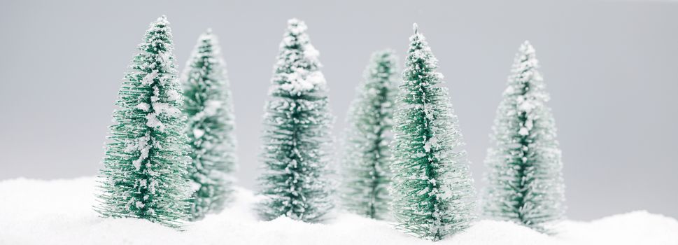 Winter wonderland with small decorative fir trees at snowfall, winter holidays concept