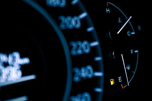 car dashboard shows low fuel warning light, selective focus