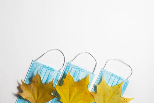 Autumn fallen leaves and medical masks on a white background.