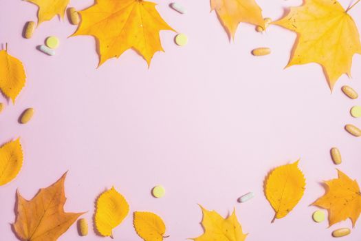 Autumn fallen leaves and medicines on pink background