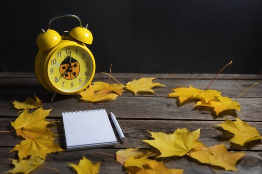 .Still life of autumn fallen leaves and office supplies on a wooden background.