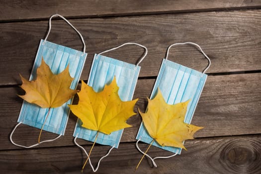 .Autumn fallen leaves and medical masks on wooden background