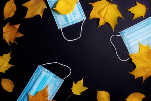 Autumn fallen leaves and medical masks on black background