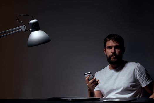 business man with mobile phone on dark background and iron lamp cropped view of work. High quality photo